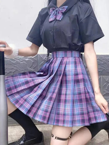 Teen girl wearing checkered pleated skirt with a gray and white wall